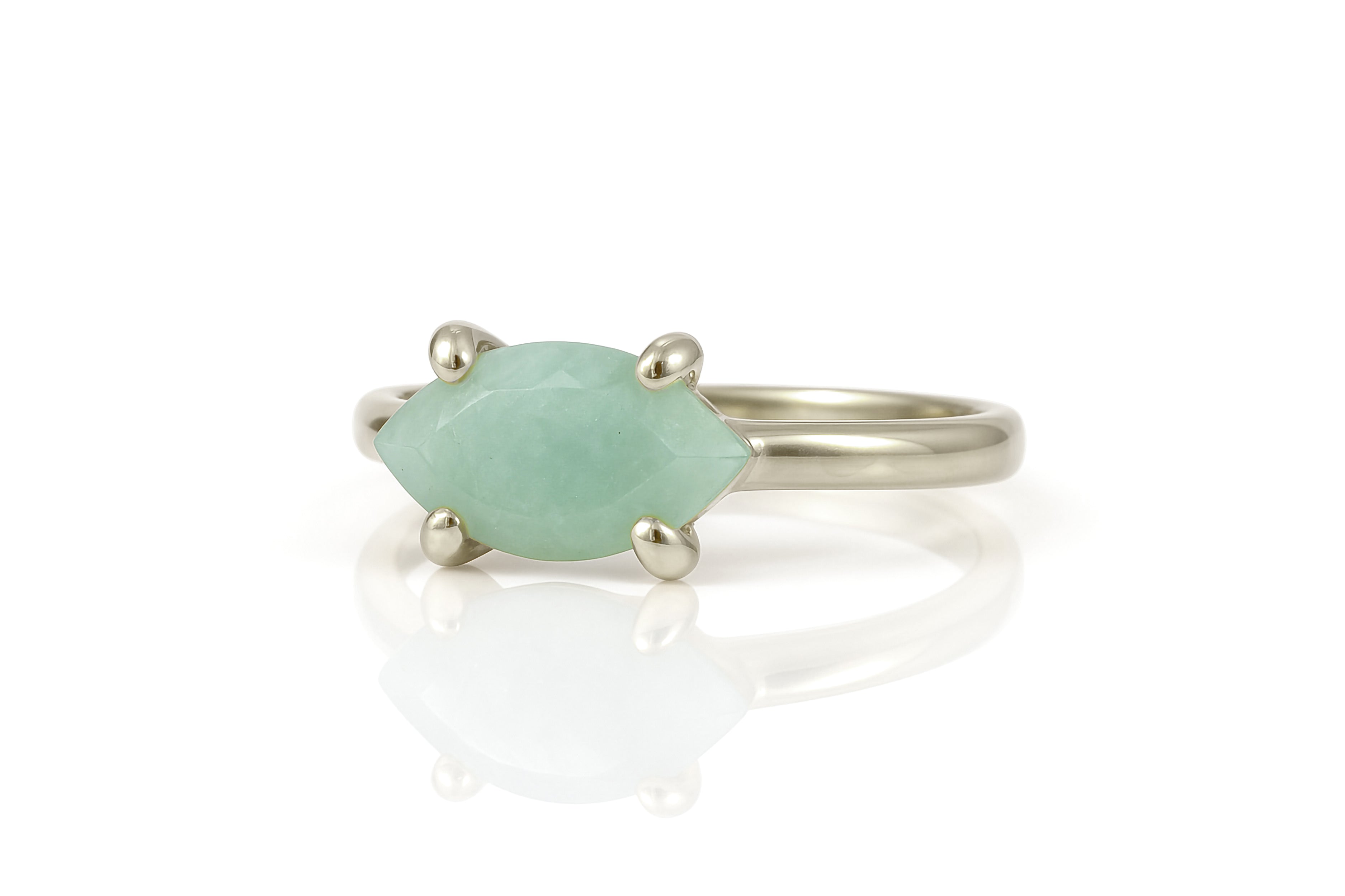 a white gold ring with a green stone