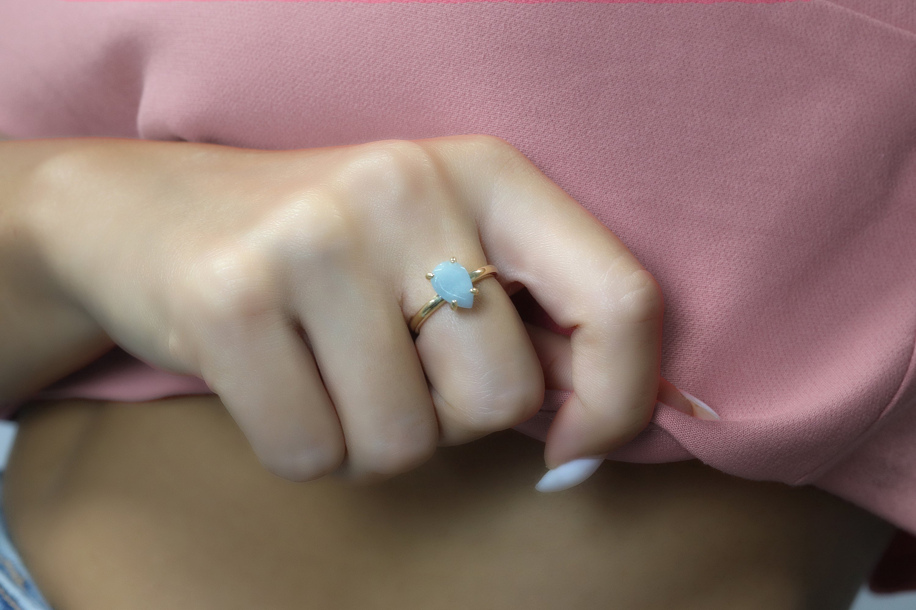 a woman wearing a pink shirt and a gold ring