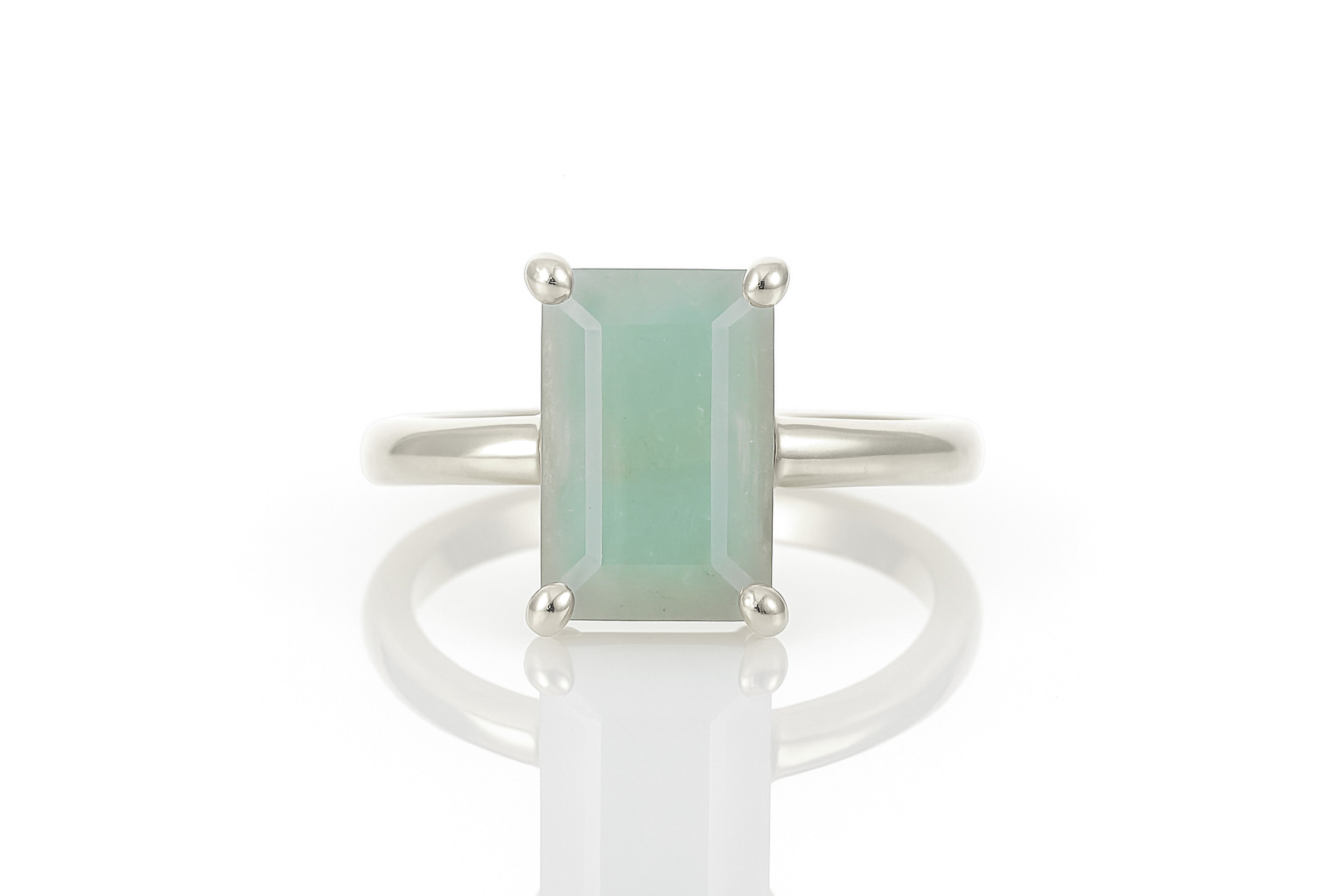 a white ring with a green stone on top of it