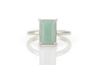 a white ring with a green stone on top of it